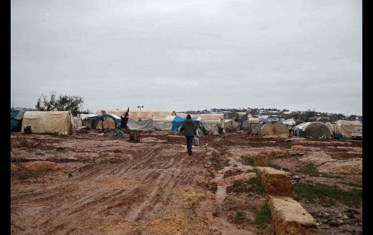 Un hombre camina en el lodo en un campamento para sirios desplazados por la guerra en la población de Atme, en la provincia de Idlib. AFP/A. Watad