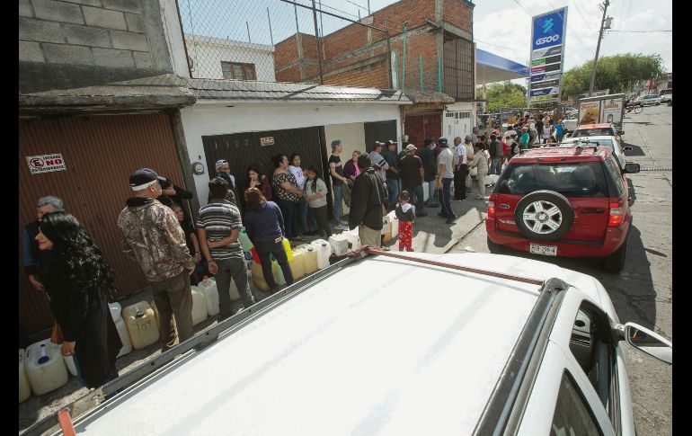 Habitantes de Morelia reúnen sus recipientes para llenarlos con combustible. EFE