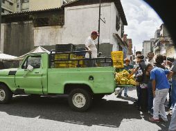 Un grupo de personas busca alimentos en los alrededores de un mercado de la capital venezolana. AFP