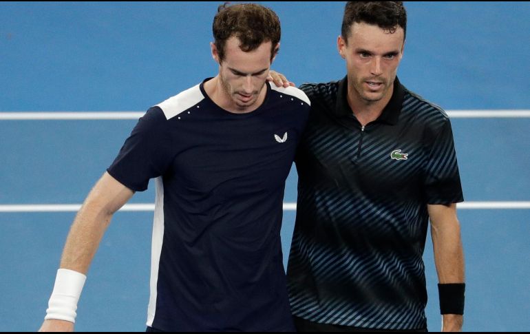 Murray, cojeante, se apoya en Roberto Bautista para salir de la cancha. AP