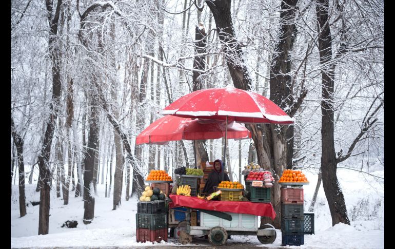Un vendedor de fruta espera la llegada de clientes durante una nevada a las afueras de Srinagar, India. AFP/T. Mustafa