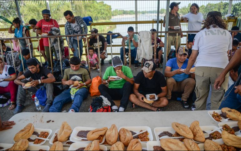 Migrantes hondureños comen mientras continúan los trámites para obtener la tarjeta humanitaria del Instituto Nacional de Migración. EFE/L. Villalobos