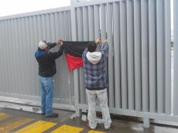 Empleados retiran una bandera rojinegra colocada a la entrada de una fábrica. TWITTER