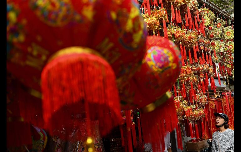 Una mujer observa decoraciones en venta en un mercado de Hanoi, Vietnam, previo a las celebraciones del año nuevo lunar. AFP/M. Vatsyayana