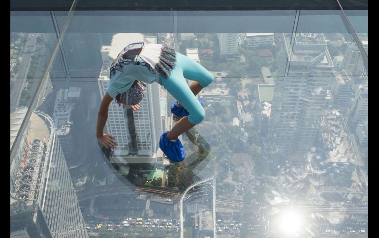 Una joven juega en el pasadizo elevado de cristal en el piso 78 del edificio King Power Mahanakhon, el mirador más alto en Bangkok, Tailandia. AFP/R. Gacad