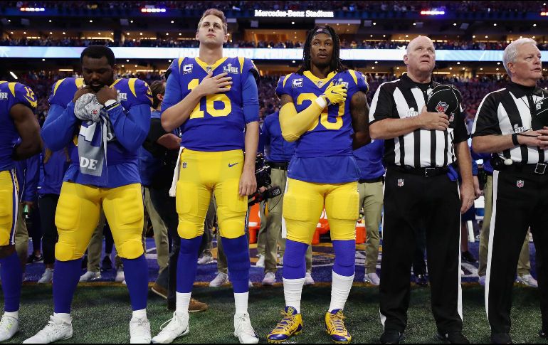 Jared Goff (16) y Todd Gurley (30) de los Rams, se ponen la mano en el corazón, pero el jugador a su derecha decide no hacerlo. AFP/J. Squire