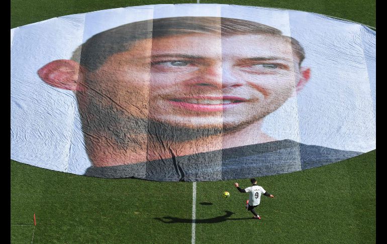 Un futbolista entrena frente a una imagen del argentino Emiliano Sala, fallecido en un accidente aéreo, previo a un partido entre el Nantes y el Nimes en la ciudad francesa de Natnes. El cuerpo del ex jugador del Nantes fue recuperado la semana pasada. AFP/L. Venance