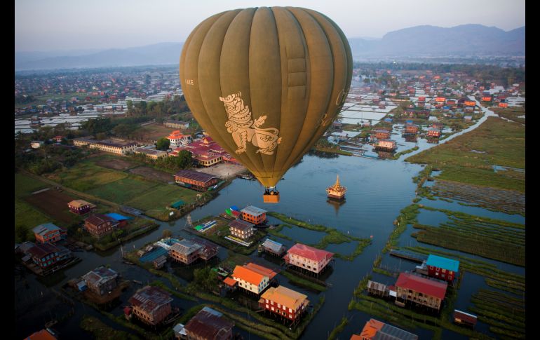 Un globo aerostático vuela sobre casas tradicionales sobre pilotes en el lago Inle, en el Estado Shan de Birmania. AFP/Y. Aung