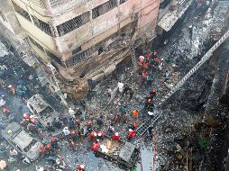 Varios bomberos inspeccionan los escombros tras el incendio declarado en la madrugada de este jueves en el barrio Chawkbazar. EFE/M. Alam