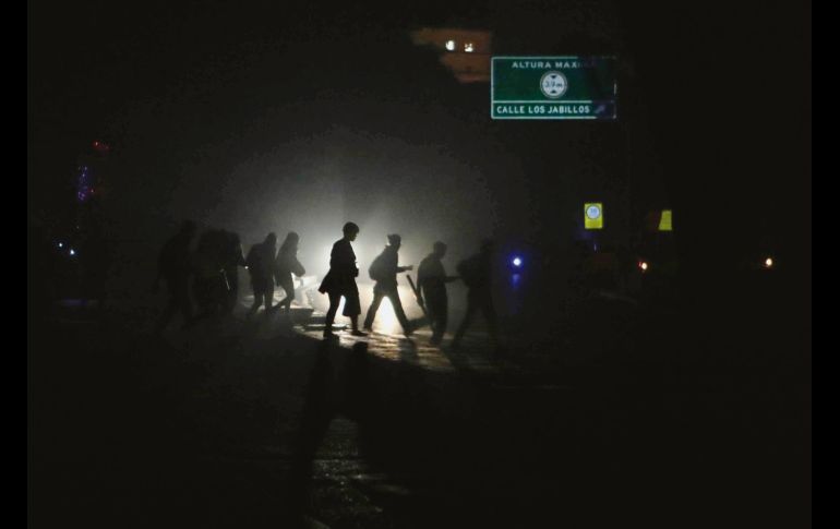 Transeúntes captados en una calle a oscuras por la falta de energía en Caracas. Desde el jueves, Venezuela sufre un nuevo apagón que afecta a varios estados de ese país. EFE