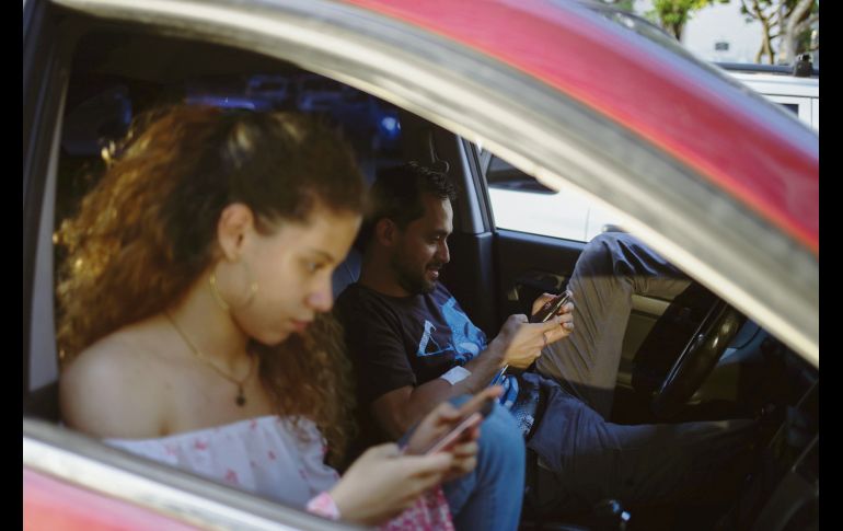 Ciudadanos verifican sus teléfonos móviles en un área de conectividad WiFi. AFP