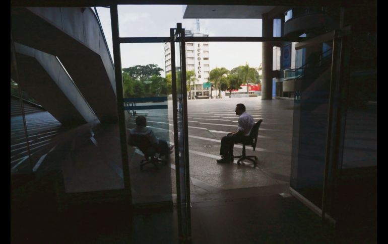 Dos guardias de seguridad se sientan en la entrada de un centro comercial que permanece cerrado, debido a la falta de electricidad que afecta a Venezuela desde el jueves. AFP