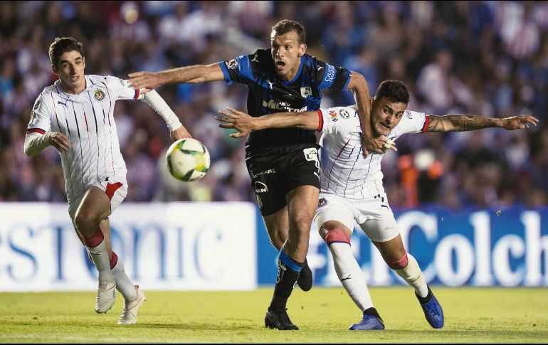 Isaac Brizuela y Alexis Vega, de Chivas, intentan superar la marca de Diego Novaretti, de los Gallos, durante el juego de ayer en Querétaro. MEXSPORT