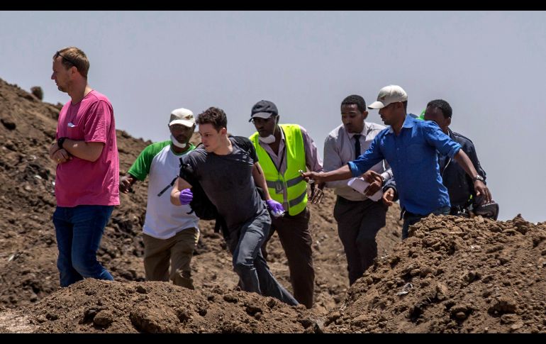 Un familiar de una víctima intenta escapar de la zona de seguridad para ver el sitio de investigación bloqueado.