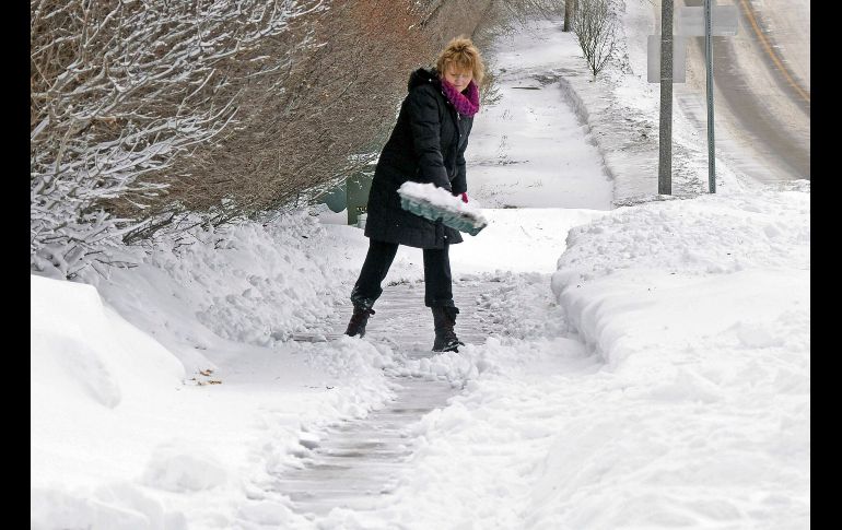 Una mujer despeja la acera aguera de su casa en Bismarck, Dakota del Norte.