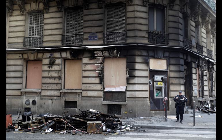 Policías vigilan afuera de una sucursal bancaria quemada.
