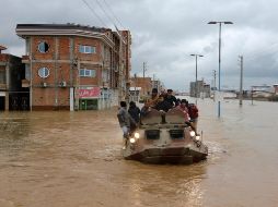 Un vehículo militar traslada a varios damnificados a través de una calle inundada. AP/M. Esmaeilzadeh