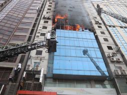 Los bomberos, con largas escaleras, rompieron ventanas para intentar crear vías de escape. Más de una hora después de que empezara el incendio, todavía se veía gente en la planta 13 y 14 pidiendo ayuda. EFE/ M. Alam