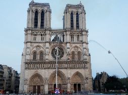 Miembros de la brigada de bomberos de París rocían agua sobre la fachada de la catedral de Notre Dame este lunes, en París. EFE/P. Wojazer