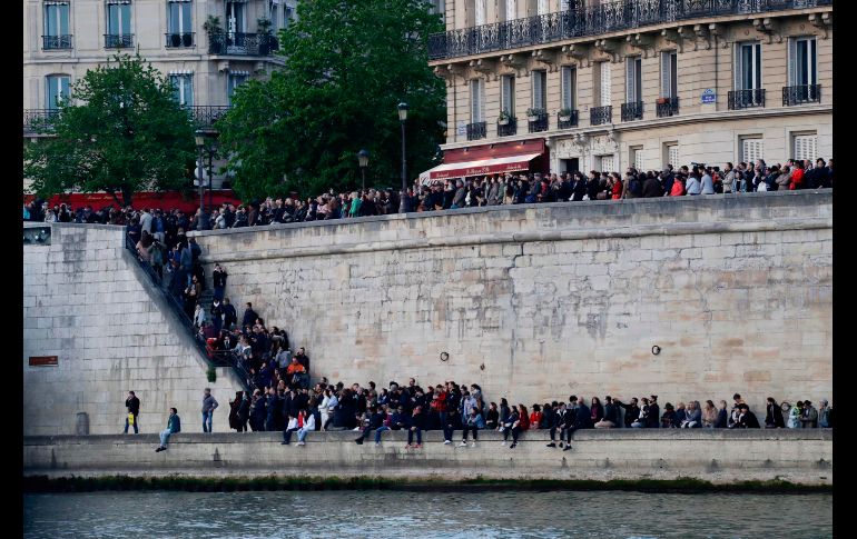 Personas observan desde una orilla del río Sena. AFP/T. Samson