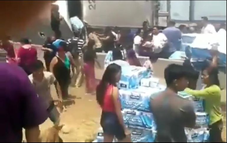 Las personas abrieron la caja del tráiler para sacar los paquetes y pasarlos a quienes los quisieran a pesar de la presencia de policías. ESPECIAL