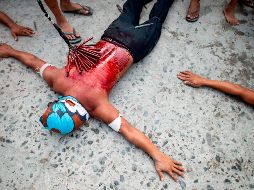 Un participante en la representación del Viernes Santo en San Juan, en la provincia filipina de Pampanga,, yace en el suelo como parte de su penitencia. AFP/N. Celis