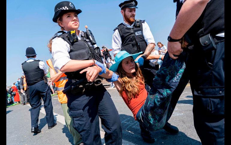 Policías arrestan a un integrante de  Extinction Rebellion en el puente de Waterloo, durante un operativo para quitar el bloqueo en esa vía. AFP/N. Halle