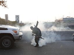 Militares que apoyan a Juan Guaidó se protegen este martes de las bombas lacrimógenas que las fuerzas de seguridad leales a Nicolás Maduro lanzan en la base militar La Carlota, en Caracas. EFE/R. Peña