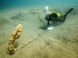 El elemento mide 2.59 metros de largo en su caña y conserva no sólo sus dos brazos de 33 centímetros cada uno, sino también su arganeo y parte de su cepo de madera. EFE/INAH