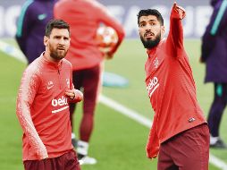 Lio y Luis Suárez dialogan en la grama de Anfield, donde hoy van por el ansiado pase al partido por el título. EFE