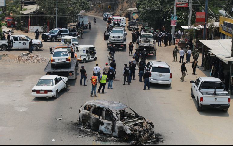 Elementos del Ejército Mexicano y la Policía Federal ingresan al poblado de Xaltianguis, donde  se aprecia un vehículo calcinado y varios más dañados por las balas. EFE/D. Guzmán