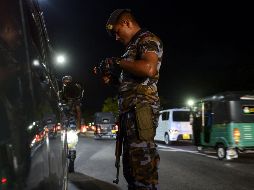 Un elemento de seguridad inspecciona un vehículo en un retén en Colombo. AFP/L. Wanniarachchi