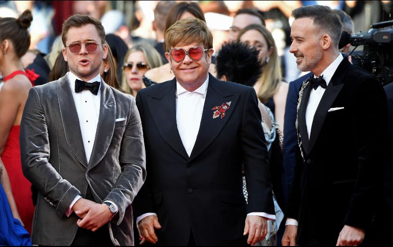 Junto a Elton Jhn le acompañan su esposo David Furnish y al actor Taron Egerton. AFP / C. Simon