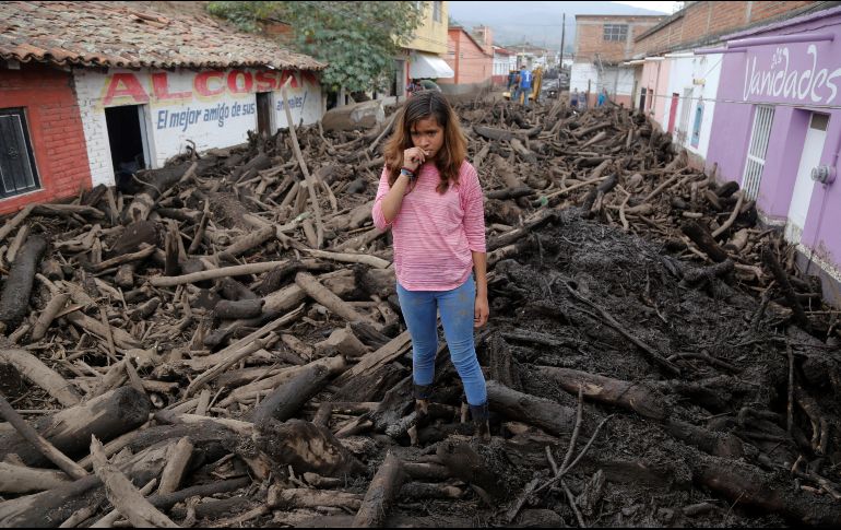 Una joven permanece entre la empalizada arrastrada por el afluente de un río, luego de las fuertes lluvias en San Gabriel. EFE / F. Guasco