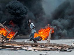 Un hombre pasa frente a una barricada en llamas este lunes, en Puerto Príncipe. EFE/J. Herve
