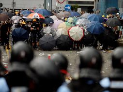 Decenas de protestantes con paraguas encaran a la policía, este miércoles en Hong Kong. EFE/V. Yuen