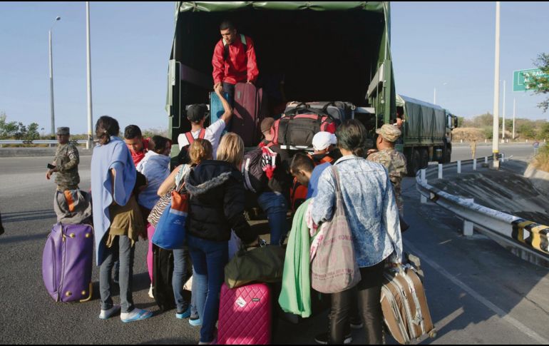Venezolanos suben a un camión militar en Perú. AP