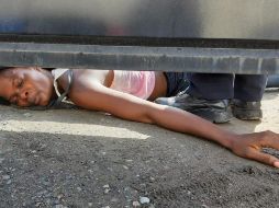 Una inmigrante haitiana se arrastra por debajo de una puerta en busca de ayuda para ella y su hijo, desde el interior del albergue Siglo XXI, en Tapachula. Demanda atención médica, alimentación y agilización de trámites migratorios. EFE/J. Blanco