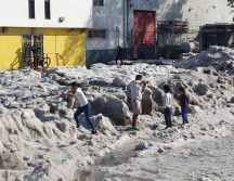 En las calles aledañas, otros vecinos armados con escobas y palas expulsan el hielo del interior de sus casas. Mientras vecinos y curiosos observan el hielo. EL INFORMADOR / J. Armendáriz