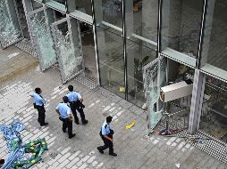 Policías vigilan hoy afuera del recinto legislativo en Hong Kong, que presenta daños tras las protestas de la víspera. AFP/H. Retamal