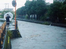 Un hombre capta el crecido río Wada en Kagoshima, en la isla de Kyushu. AFP/JIJI PRESS