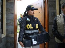 Una oficial de policía sale de la casa del expresidente Humala con un escáner recogido como posible prueba. AP/M. Mejía