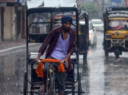Un hombre conduce su bicicleta en medio de una fuerte lluvia en la India. AFP / N. Nanu