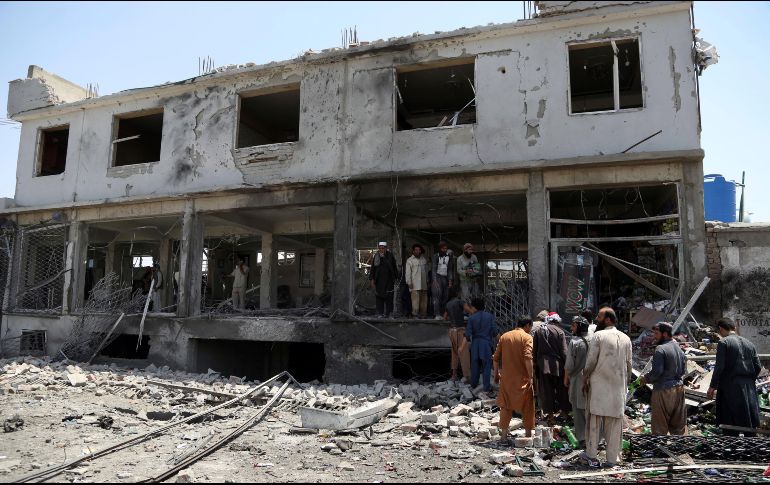 Un grupo de hombres afganos buscan restos de sus mercancías entre los escombros de sus tiendas después de un ataque suicida en Kabul, Afganistán. AP / R. Gul