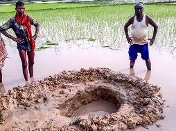 Habitantes posan junto al cráter que dejó el objeto no identificado. AFP