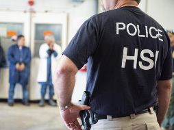Un agente vigila a inmigrantes detenidos ayer durante una redada en Mississippi.  AFP/ICE