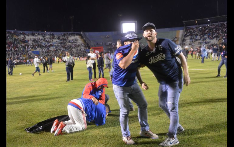 Aficionados saltaron al campo luego de que policías lanzaron gas lacrimógeno. AP/V. Colindres
