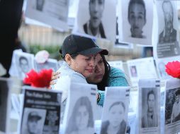 Dos mujeres observan fotografías de personas desaparecidas este viernes, en las afueras del Palacio Nacional, en la Ciudad de México. EFE/M. Guzmán