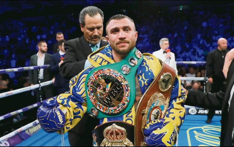 Vasyl Lomachenko posa con sus tres cinturones de monarca de peso Ligero. AFP