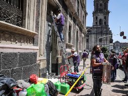 Trabajadores restauran y arreglan las fachadas de edificios y comercios dañados el jueves por encapuchados. NOTIMEX/Q. Blanco